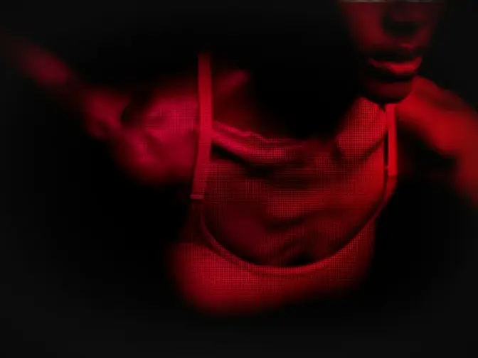 A bust of a fit African-American woman in red light showing movement